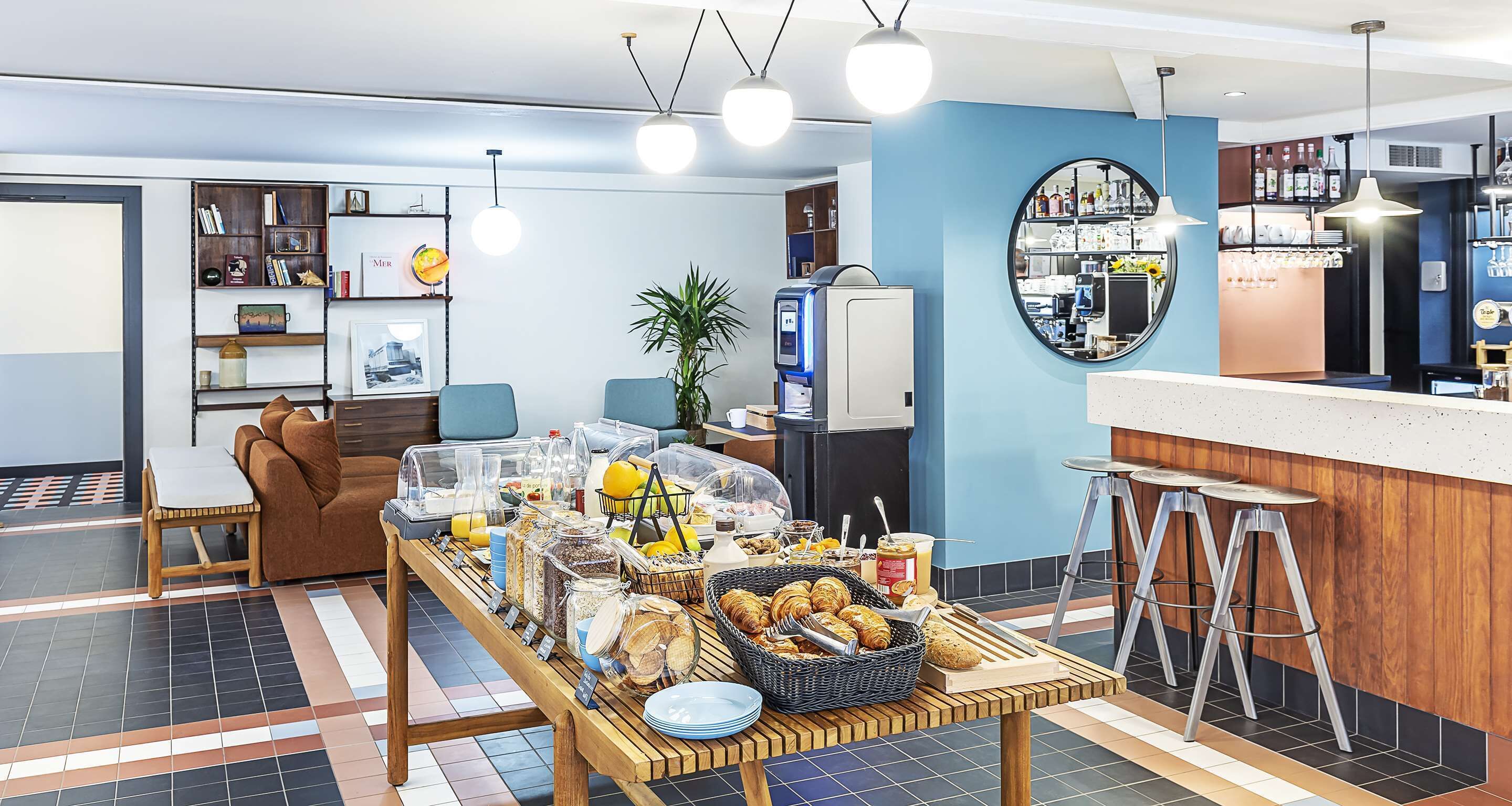 Een ontbijtbuffet met diverse gerechten, een zithoek met een bank en stoelen, en een bar met krukjes.