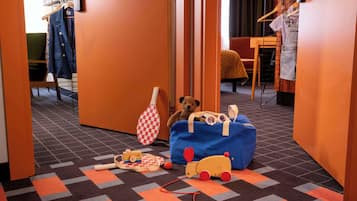 A hotel lobby with a checkered carpet, a teddy bear, a blue suitcase, and a toy train.