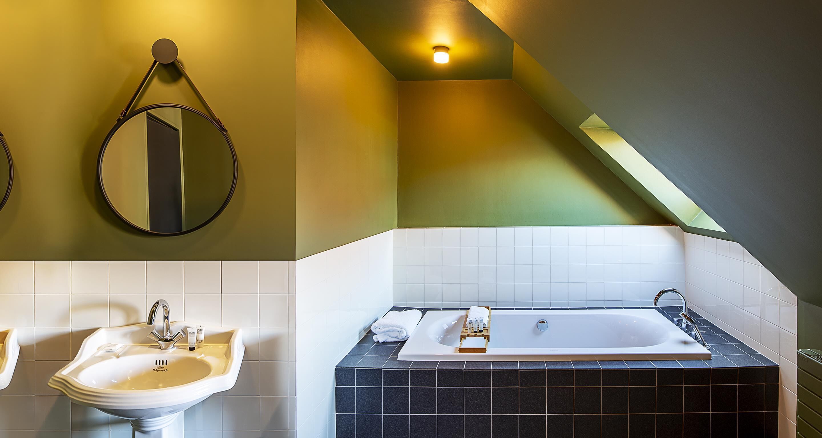 A bathroom with a sink, mirror, and bathtub.