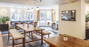 A modern dining area with wooden tables and benches, large windows with city views, and pendant lighting. - Best Western Plus Hotel Cargo (Dunkirk)