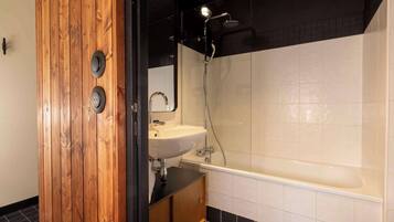 A modern bathroom with a wooden vanity, a white sink, and a bathtub.