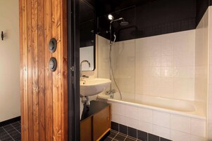Un baño moderno con tocador de madera, lavamanos blanco y bañera.