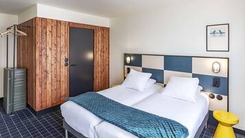 Ein Hotelzimmer mit Bett, Kleiderschrank, Spiegel und einem Bild an der Wand.