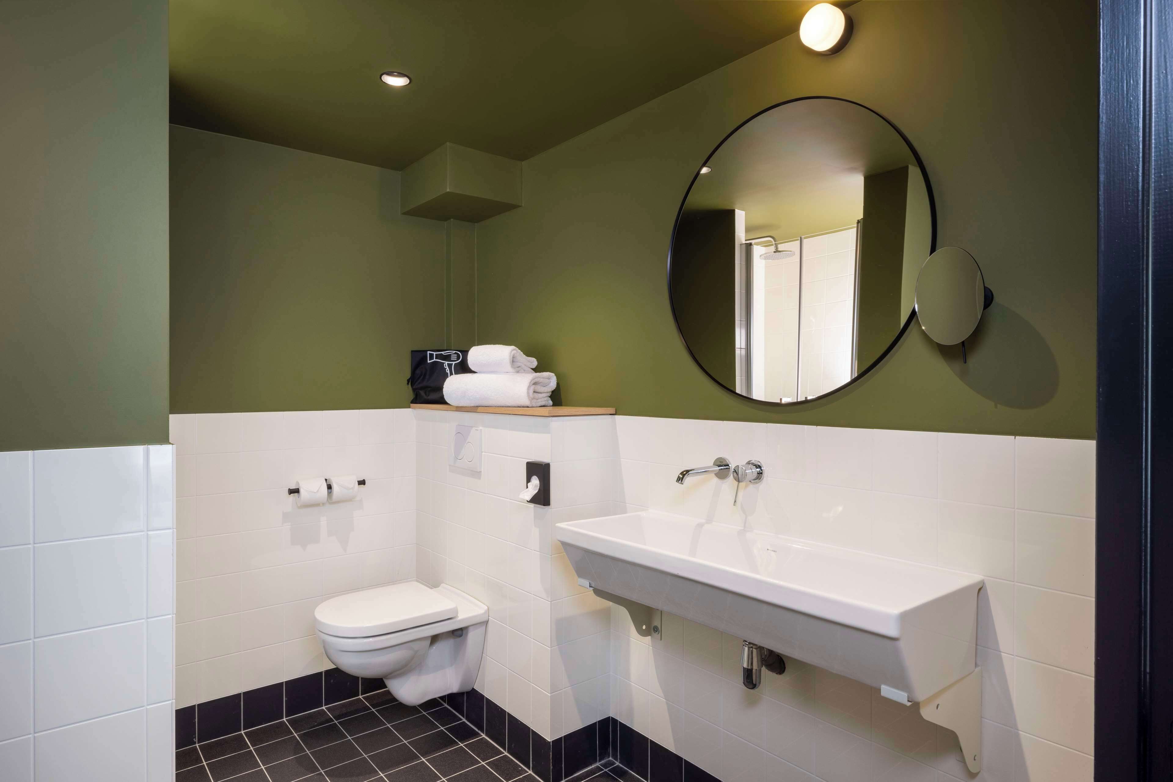 A modern bathroom with a white sink, a toilet, and a mirror.