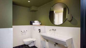 A modern bathroom with a white sink, a toilet, and a mirror.