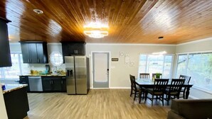 A modern kitchen with dark cabinets, stainless steel appliances, and a dining area with a wooden table and chairs. - Cozy Lake View Experience (Klamath Falls)