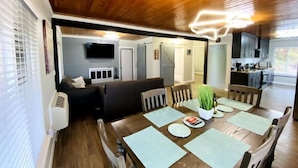 A dining area with a wooden table set for four, surrounded by chairs. A television is mounted on the wall above the seating area. - Cozy Lake View Experience (Klamath Falls)