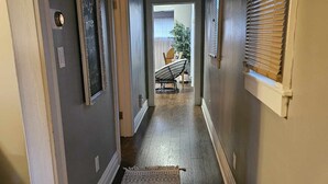 A hallway with a patterned rug, a door with a sign, and a window with blinds. - Cozy Home in Heart of Prestonsburg (Prestonsburg)