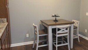 A small dining area with a table and two chairs, a light switch on the wall, and a wooden cabinet to the left. - Cozy Home in Heart of Prestonsburg (Prestonsburg)