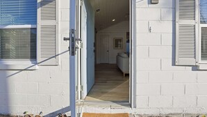 A doorway leading into a room with a wooden floor and a bed with a headboard. - Heated Pool + Putting Green | Walk to Beach (Tybee Island)