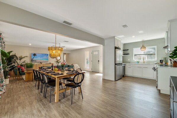 A spacious living area with a dining table, chairs, and a kitchen area with modern appliances.