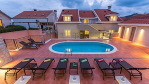 Une piscine sur le toit, dotée de chaises longues et d’une terrasse couverte.