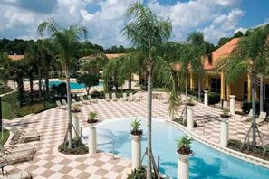 A pool area with checkered flooring, palm trees, lounge chairs, and a clear blue sky. - Magical Themed Home w/ Private Pool, by Disney (Kissimmee)