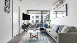Un salon moderne avec un canapé, une table basse et un téléviseur à écran plat.