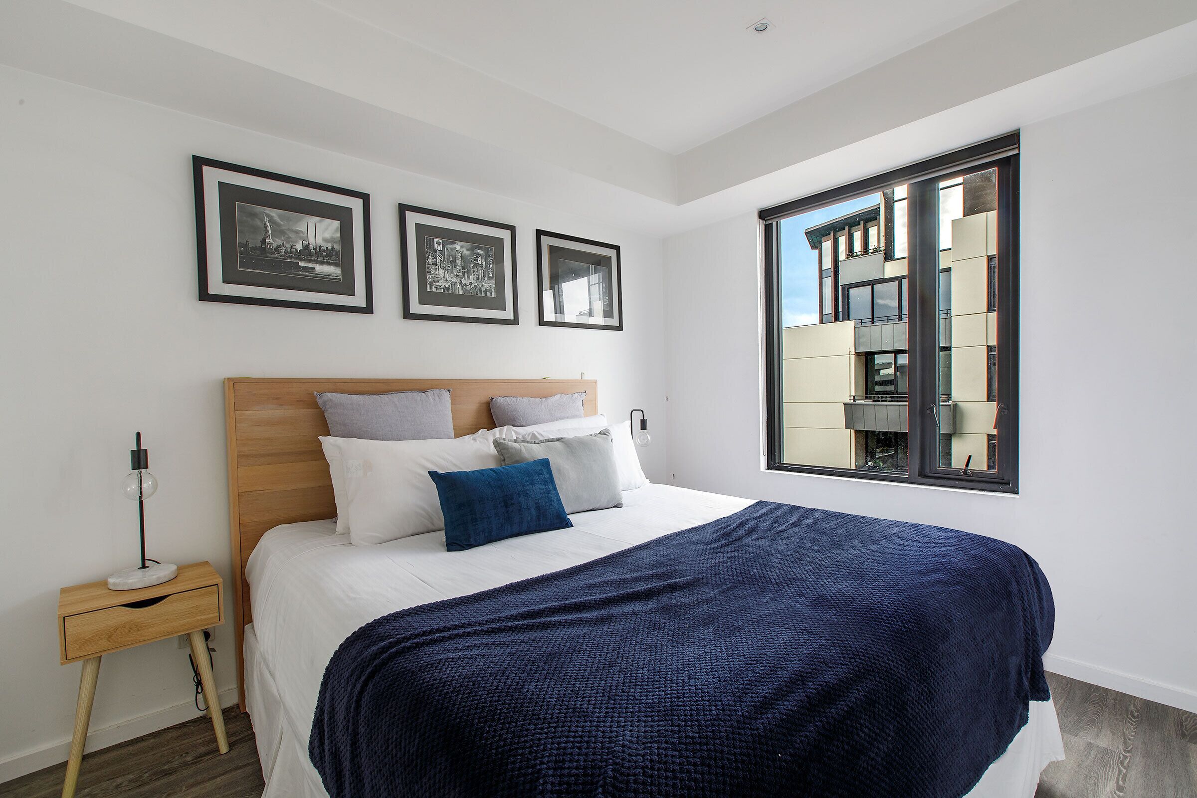 A modern bedroom with a large bed, a nightstand, and framed pictures on the wall.