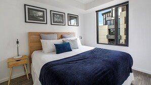 Une chambre à coucher moderne avec un grand lit, une table de chevet et des tableaux encadrés accrochés au mur.