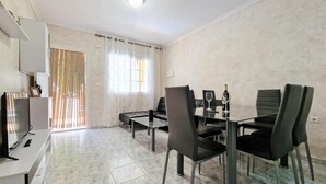A dining area with a glass table and black chairs, a sofa, and a TV on a white cabinet. - Beautiful home in Torrevieja with swimming pool (Torrevieja)
