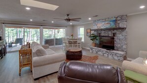A spacious living room with a stone fireplace, a leather sofa, and a dining area with a table and chairs. - Arkansas Vacation Rental on Greers Ferry Lake! (Greers Ferry)