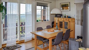 A dining area with a wooden table and chairs, a large window with a view, and a kitchen area with a grill.