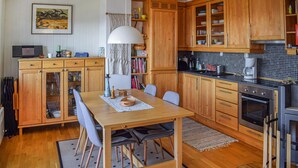 A kitchen with wooden cabinets, a dining table with chairs, a coffee maker, and a microwave.