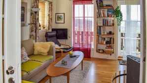 A living room with a sofa, a coffee table, a bookshelf, and a television.