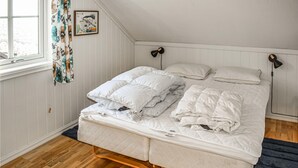A bed with white bedding, two bedside lamps, and a framed picture on the wall.