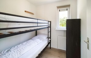 Ein Schlafzimmer mit Etagenbetten, einem Fenster und einer Heizung.