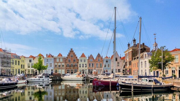 Ein Kanal mit vertäuten Booten, umgeben von farbenfrohen historischen Gebäuden.