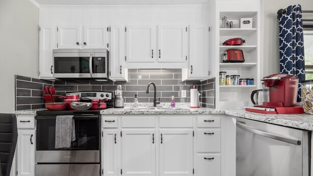 Una cocina moderna con gabinetes blancos, electrodomésticos de acero inoxidable y encimera de granito.