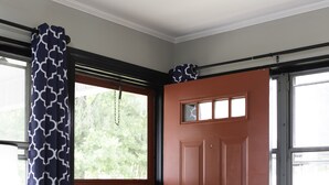 Una habitación con puerta de madera, ventana con vistas a zonas verdes y sillón de cuero marrón.