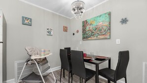 Un comedor con una mesa, sillas, una trona y obras de arte en las paredes.