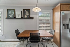 Een eetruimte met een houten tafel, zwarte stoelen en ingekaderde botanische prints aan de muur.