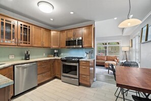 Enjoy cooking in this well-equipped kitchen with a dishwasher, stove, and microwave, and dine in the adjacent dining area with a table and chairs.