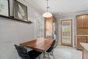 Een moderne keuken met een houten tafel, zwarte stoelen en houten keukenkastjes.