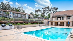 A swimming pool with lounge chairs and a covered area, surrounded by apartment buildings and greenery. - Minutes from Carlsbad Downtown and Beach (Carlsbad)