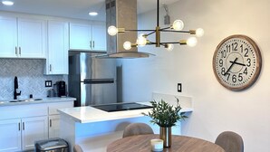 A modern kitchen with white cabinets, a stainless steel range hood, and a built-in island. - Minutes from Carlsbad Downtown and Beach (Carlsbad)