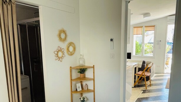 Une chambre d’hôtel avec un lit, une étagère en bois ornée d’objets décoratifs, un miroir et une vue sur l’espace extérieur.