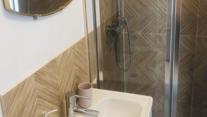 Une salle de bain avec un miroir, un lavabo et une douche.