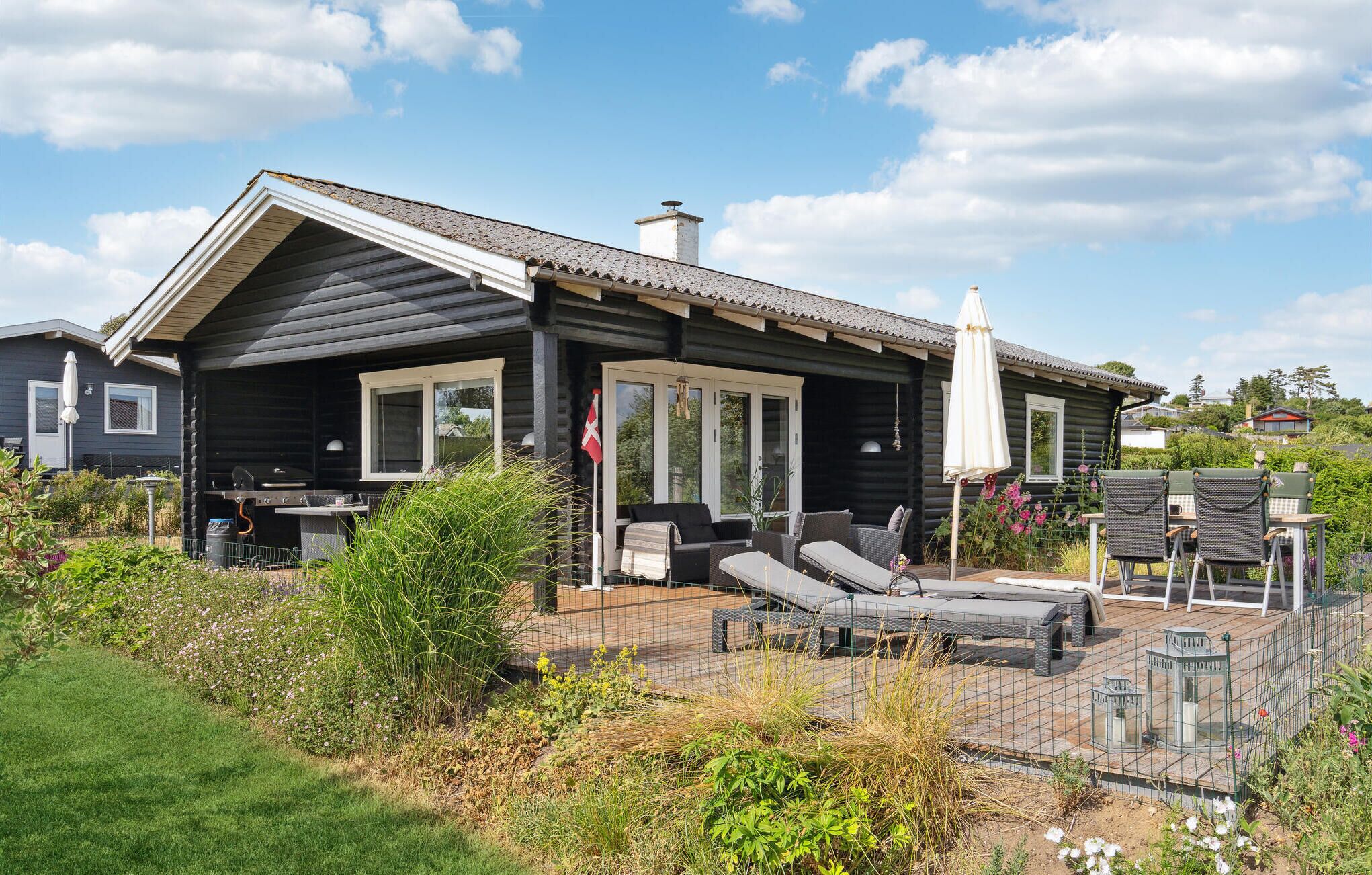 A log cabin with a patio area featuring outdoor furniture and a grill.