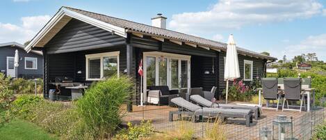 A log cabin with a patio area featuring outdoor furniture and a grill.
