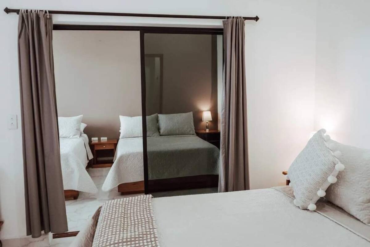 Een hotelkamer met een bed, twee nachtkastjes en een schuifdeur naar een andere kamer.