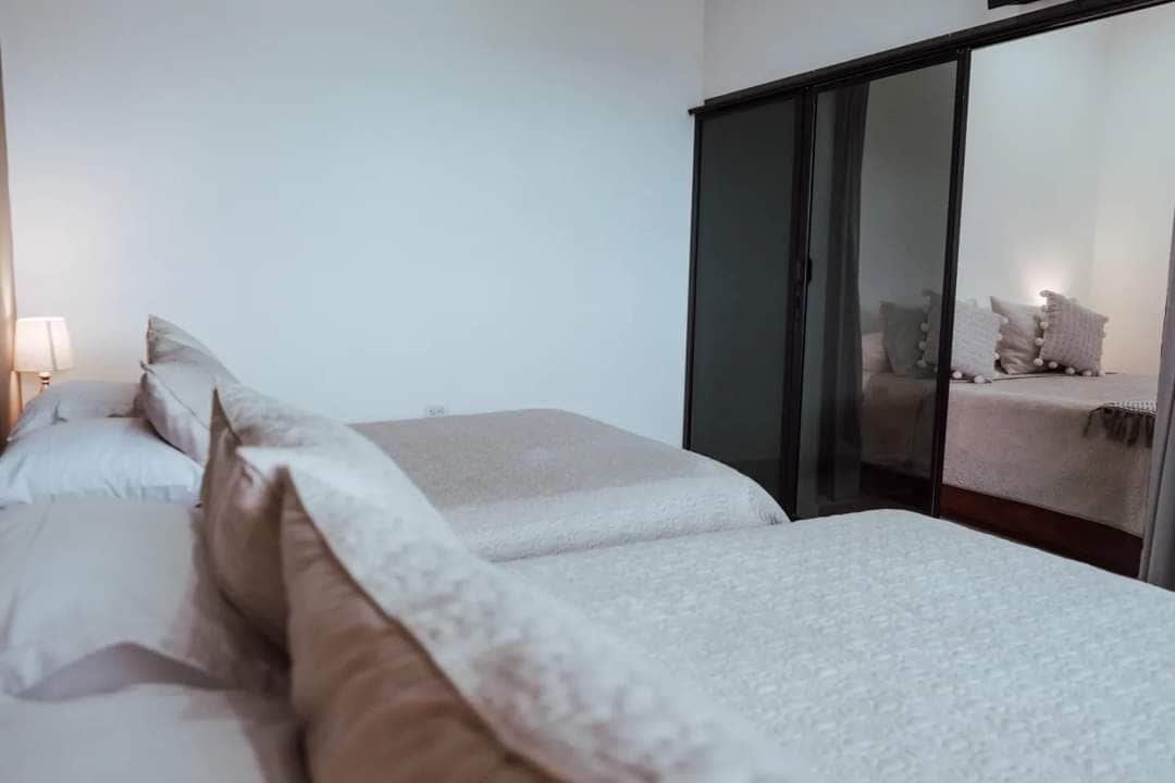 Een slaapkamer met twee bedden, een garderobe en een nachtkastje met een lamp.