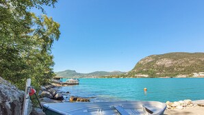 Un bote amarrado en una costa rocosa, con vista despejada a un lago tranquilo y colinas lejanas.