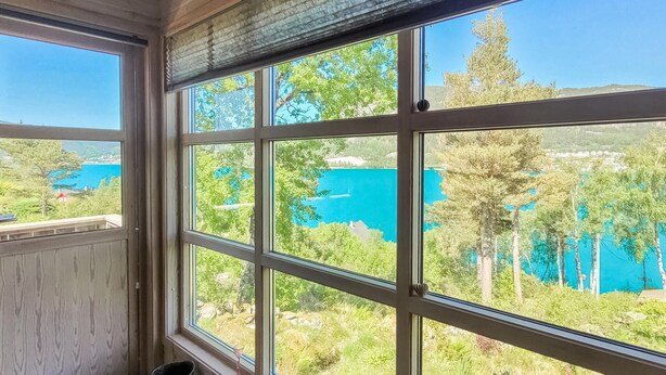 Habitación con amplios ventanales que ofrecen vistas a un lago y follaje circundante.