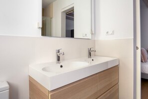 Bathroom features a white vanity, sink, and toilet, with a large mirror above.