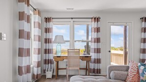 Een slaapkamer met een bed, een bureau met stoel, een raam met gordijnen en uitzicht op het buitengebied.