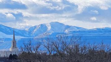 Una iglesia con una aguja alta, rodeada de montañas nevadas y un cielo despejado.
