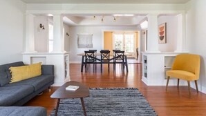 A modern living room with a sofa, a coffee table, and a yellow armchair. There is a dining area with a table and chairs in the background. - Spacious retreat with outdoor dining, patios and views (Seattle)