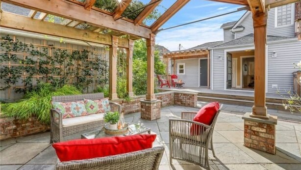 A covered patio area with wicker furniture and a brick wall. - Spacious retreat with outdoor dining, patios and views (Seattle)