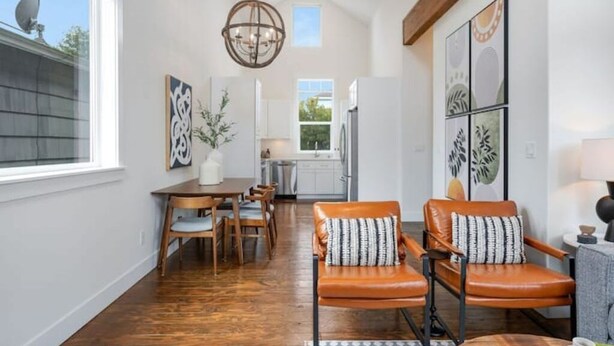 Un vaste espace dédié à la salle à manger, avec une table et des chaises en bois, un lustre et des œuvres d’art accrochées aux murs.